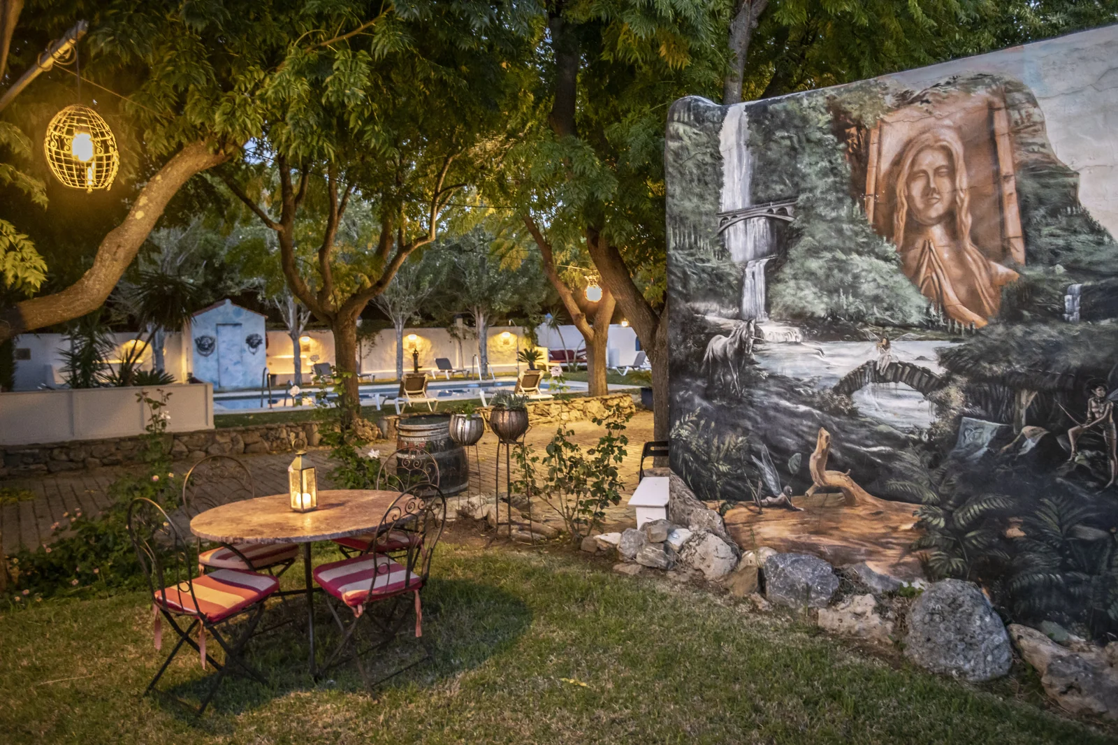 Jardín al atardecer con mural artístico y velas