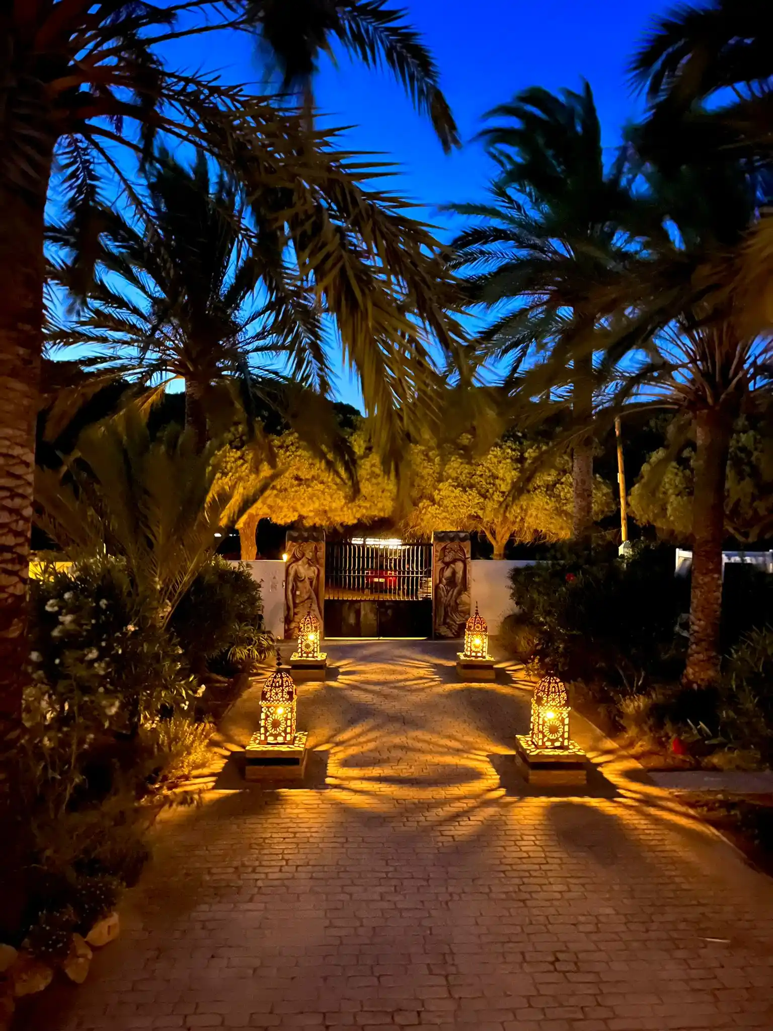 Entrada mágica iluminada con faroles moriscos y palmeras en Paraíso Perdido Conil